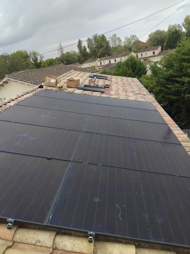Panneaux solaires installés sur un toit, avec un ciel nuageux en arrière-plan.